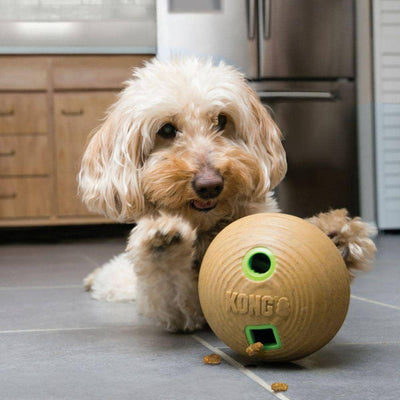 KONG Bamboo feeder ball i brun med grønne huller og en hund der leger med den 